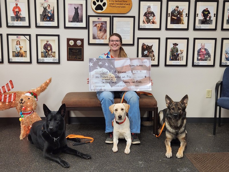 Andie, trainer at Patriot K9s of Wisconsin, receives check from the Kelly Family with the K9 dogs in December 2024.